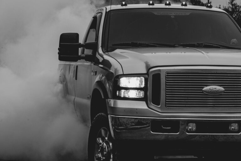 A black and white image of a Ford pickup truck emitting smoke, showcasing strength and power.